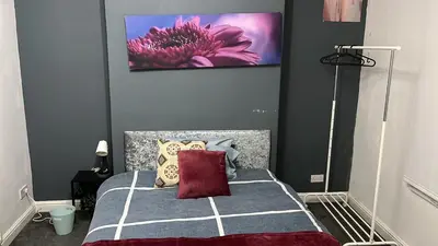a bedroom with a bed with a pink flower painting on the wall at Regina Pacis contractor place near the city in Liverpool