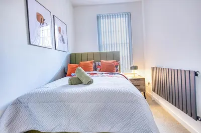 a bedroom with a large bed with orange pillows at Central 2 beds APT with FREE parking, Sleeps 6 in Liverpool