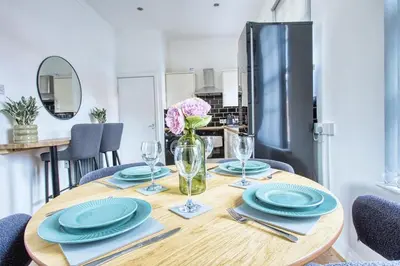a table with plates and glasses and a refrigerator at Central 2 beds APT with FREE parking, Sleeps 6 in Liverpool