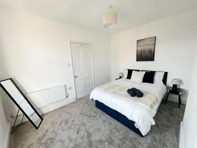 a white bedroom with a large bed and a mirror at Modern 3-Bed House Near Attractions & Beach in Blackpool