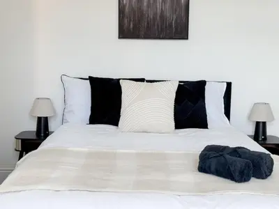 a white bed with black and white pillows and two lamps at Modern 3-Bed House Near Attractions & Beach in Blackpool