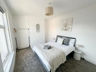 a white bedroom with a large bed and a window at Modern 3-Bed House Near Attractions & Beach in Blackpool