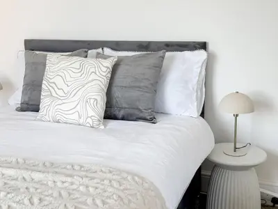 a bedroom with a white bed with pillows and a lamp at Modern 3-Bed House Near Attractions & Beach in Blackpool