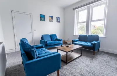 a living room with blue chairs and a table at 5 Bed Stay For Contractors And Families in Morecambe