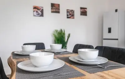 a wooden table with white cups and plates on it at 5 Bed Stay For Contractors And Families in Morecambe