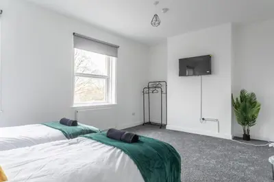 a bedroom with two beds and a tv on the wall at 5 Bed Stay For Contractors And Families in Morecambe