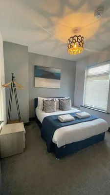 a bedroom with a large bed and a chandelier at Delamore Place Cozy Home 3BR near City in Liverpool