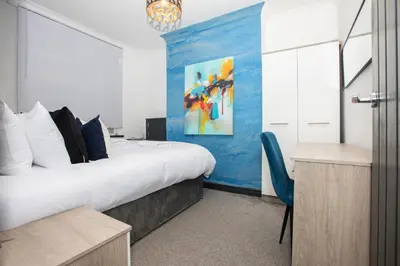 a bedroom with a large bed and a blue wall at Delamore Place Cozy Home 3BR near City in Liverpool