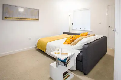 a bedroom with a bed with a couch and a table at Comfortable 3-bedroom Bolton home in Westhoughton