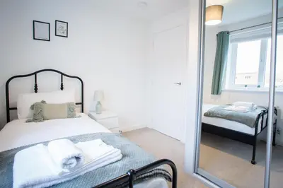 a bedroom with a bed with a mirror and a window at Comfortable 3-bedroom Bolton home in Westhoughton