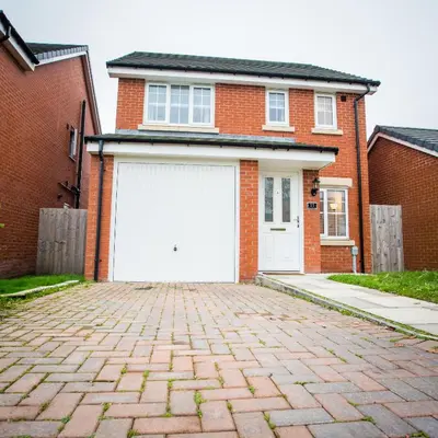 a red brick house with a white garage at Comfortable 3-bedroom Bolton home in Westhoughton