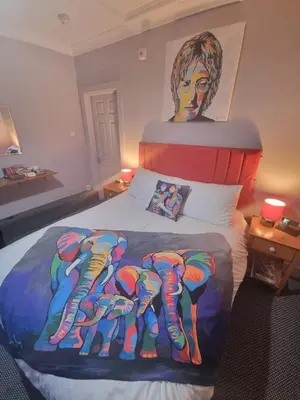 a bedroom with a bed with a painting on it at Pride Lodge in Blackpool