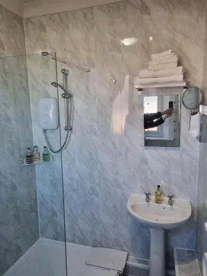 a person taking a picture of a bathroom with a shower at Pride Lodge in Blackpool