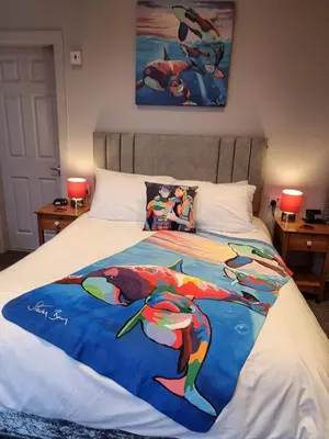 a bed with a colorful blanket on top of it at Pride Lodge in Blackpool