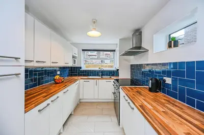 a kitchen with white cabinets and blue tiles at 4 bed house Liverpool L7 in Liverpool