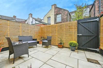 a wooden fence with chairs and a table on a patio at 4 bed house Liverpool L7 in Liverpool