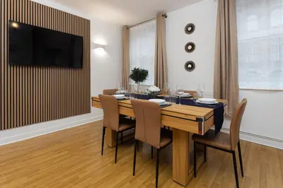 a dining room with a table and chairs and a television at Harrington Chambers by Charming Apartments - Pool Table & Ping Pong in Liverpool