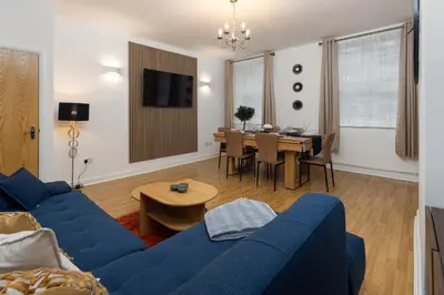 a living room with a blue couch and a dining room at Harrington Chambers by Charming Apartments - Pool Table & Ping Pong in Liverpool