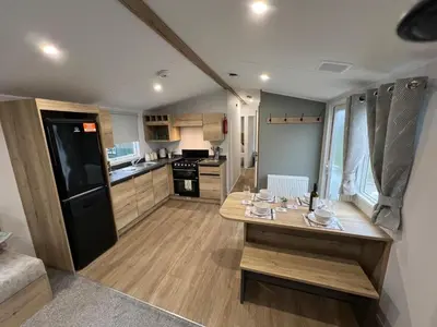a kitchen with a wooden table and a black refrigerator at 2025 Willerby Ellerton Static Caravan in Morecambe