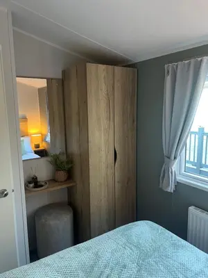 a bedroom with a wooden cabinet and a bed at 2025 Willerby Ellerton Static Caravan in Morecambe