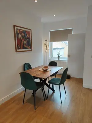 a dining room with a wooden table and green chairs at luxury Maisonette near beach in Morecambe