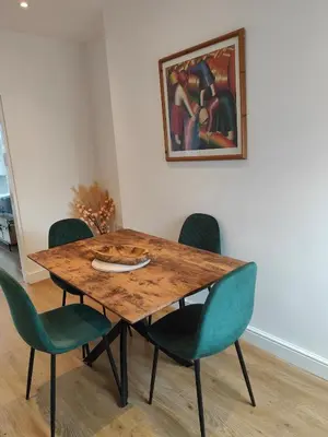 a dining room table with green chairs and a painting at luxury Maisonette near beach in Morecambe