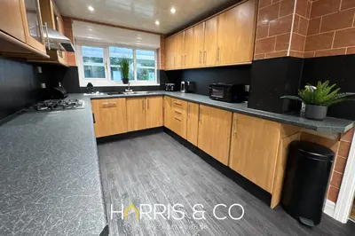 a large kitchen with wooden cabinets and a sink at Sandringham & Spa Villa in Thornton
