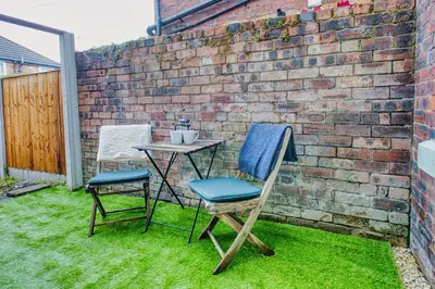 two chairs and a table next to a brick wall at Modern 3-Bed Home Sleeps 6 with Parking & Fast WiFi Perfect for Contractors & Long Stays in Saint Helens