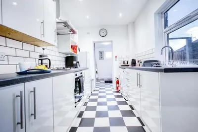 a kitchen with white cabinets and a checkered floor at Modern 3-Bed Home Sleeps 6 with Parking & Fast WiFi Perfect for Contractors & Long Stays in Saint Helens