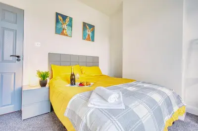 a bedroom with a yellow bed with a bowl of fruit on it at Modern 3-Bed Home Sleeps 6 with Parking & Fast WiFi Perfect for Contractors & Long Stays in Saint Helens