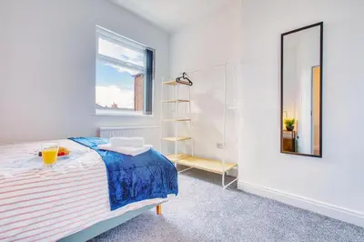 a white bedroom with a bed and a mirror at Modern 3-Bed Home Sleeps 6 with Parking & Fast WiFi Perfect for Contractors & Long Stays in Saint Helens