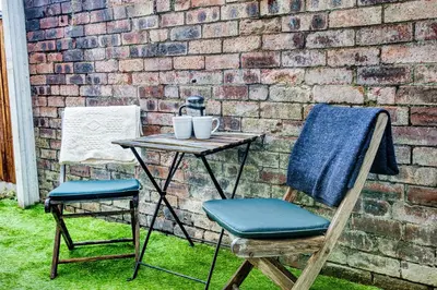 a table and two chairs next to a brick wall at Modern 3-Bed Home Sleeps 6 with Parking & Fast WiFi Perfect for Contractors & Long Stays in Saint Helens