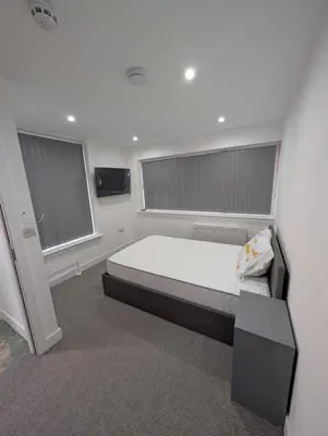 a bedroom with a large bed and two windows at Park Lodge Preston in Preston