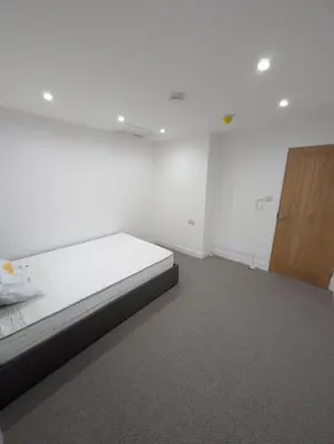 a white room with a bed and a wooden door at Park Lodge Preston in Preston