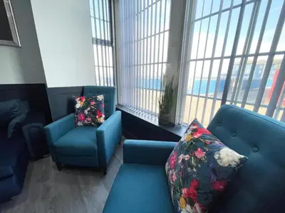 a living room with two blue chairs and windows at Serenity Wembley in Blackpool