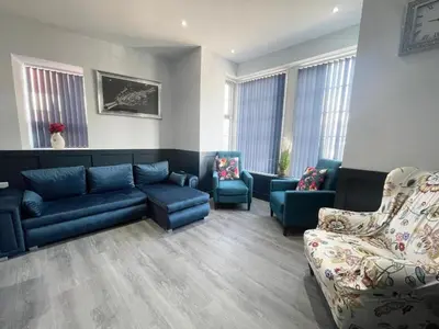 a living room with blue couches and chairs at Serenity Wembley in Blackpool