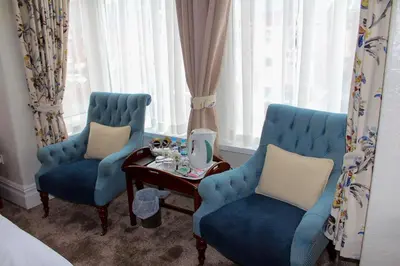two blue chairs and a table in a room with windows at The Gaydon in Lytham St Annes