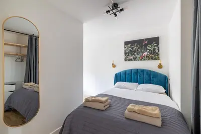 a bedroom with a blue bed and a mirror at Chic 1BHK in West London in Lytham St Annes