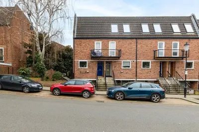 three cars parked in front of a brick house at Chic 1BHK in West London in Lytham St Annes