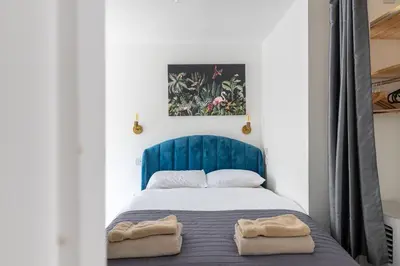 a bedroom with a blue bed with two towels on it at Chic 1BHK in West London in Lytham St Annes