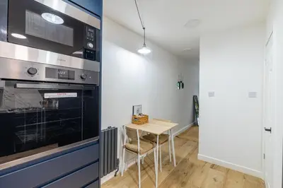 a small kitchen with a table and a stove at Chic 1BHK in West London in Lytham St Annes
