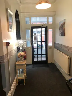 a hallway with a door and a table with a lamp at West Vale Villa in Blackpool