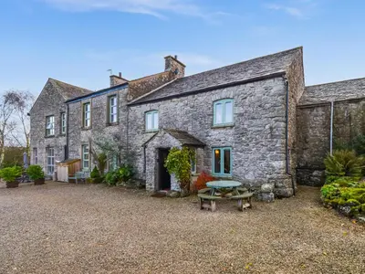 an old stone house with a picnic table in front of it at The Old Farm House in Beetham