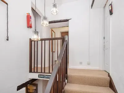 a hallway with stairs with a fire hydrant and chandeliers at The Old Farm House in Beetham