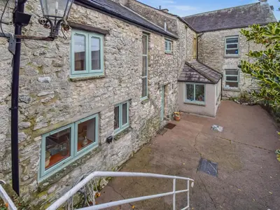 a stone house with a courtyard in front of it at The Old Farm House in Beetham