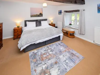 a bedroom with a large bed and a rug at The Old Farm House in Beetham
