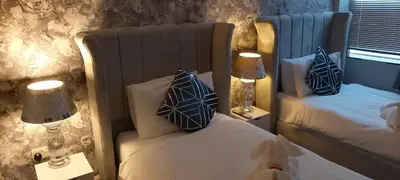 a bedroom with two beds with pillows and two lamps at The Dreamcatcher Hotel in Blackpool