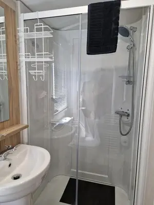 a white bathroom with a shower and a sink at Our Sea View - Heysham in Heysham