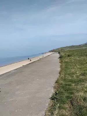 an empty beach with people walking on the sand at Our Sea View - Heysham in Heysham