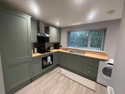 a kitchen with green cabinets and a washer and dryer at Rose Cottage by Sasco in Blackpool
